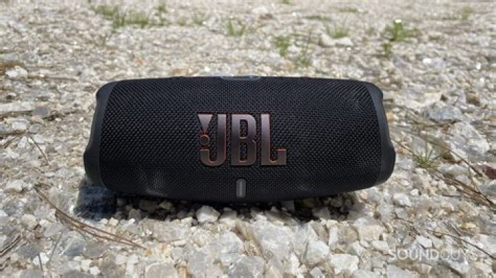 jbl charge 5 outdoors rocky ground JBL Charge 5 resting on rocks and grass.